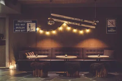 a restaurant with tables and lights on the wall at Gudbrandsgard Hotel in Kvitfjell