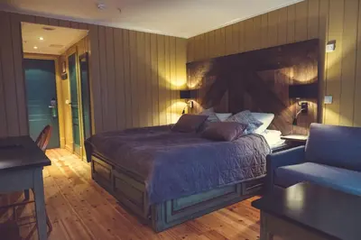 a bedroom with a large bed and a chair at Gudbrandsgard Hotel in Kvitfjell