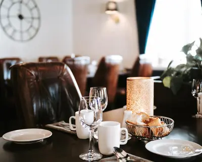 a table with glasses and a plate of food on it at Bårdshaug Herregård in Orkanger