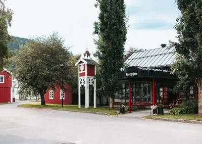 a red building with a clock tower next to a street at Bårdshaug Herregård in Orkanger