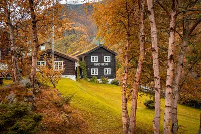 a black house on a hill with trees at Røisheim Hotel & Skysstasjon in Lom