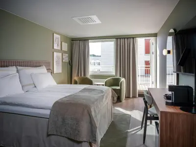 a hotel room with a bed and a desk and a television at Quality Hotel Grand Kristiansund in Kristiansund