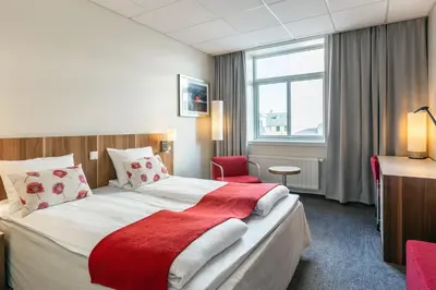 a hotel room with a large bed with a red blanket at Quality Hotel Grand Kristiansund in Kristiansund