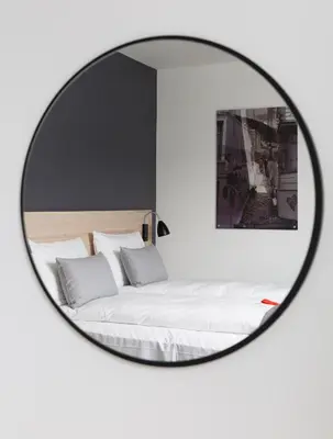 a mirror reflecting a bed with white sheets and pillows at Citybox Bergen City in Bergen
