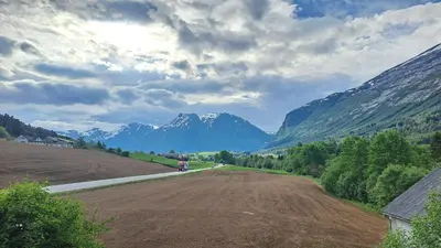 a tractor on a dirt road with mountains in the background at Elvebakk Bed & Breakfast in Reed