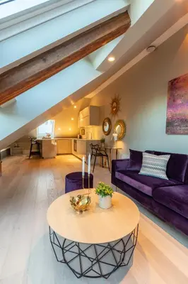 a living room with a table and a purple couch at 2 Døtre Apartments by Hotel Park in Bergen