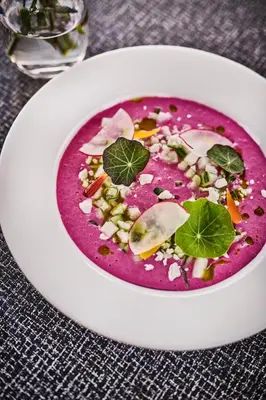 a white plate with a red soup with vegetables in it at Energihotellet in Nesflaten