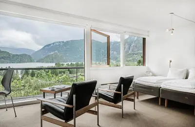 a bedroom with a bed and chairs and a large window at Energihotellet in Nesflaten