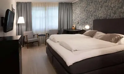 a hotel room with a large bed and a table at Best Western Tingvold Park Hotel in Steinkjer