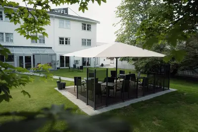a table and chairs under a white umbrella in a yard at Best Western Tingvold Park Hotel in Steinkjer