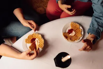 two people sitting at a white table with waffle food at Best Western Tingvold Park Hotel in Steinkjer
