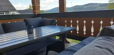 a table and chairs on a balcony with a view of mountains at Solbjørnlia Apartments in Trysil