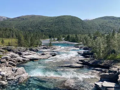 a river in the mountains with rocks and trees at Voss Mountain Lodge in Mjølfjell