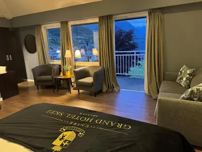 a hotel room with a bed and a view of a balcony at Grand Hotel Skei - Unike Hoteller in Skei