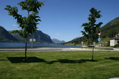 two trees in a field next to a body of water at Grand Hotel Skei - Unike Hoteller in Skei