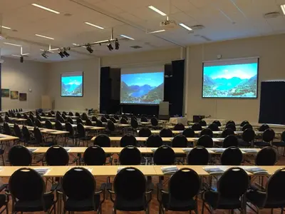 a large room with tables and chairs and screens at Grand Hotel Skei - Unike Hoteller in Skei