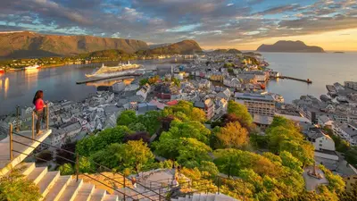 a woman standing on the edge of a city overlooking a harbor at Hotel Noreg in Ålesund