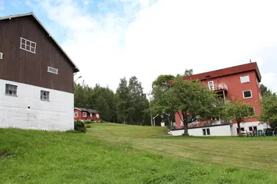 a barn and a red building on a grass field at Smedsgården Hotel in Nesbyen