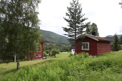 a small red house with a tree in a field at Smedsgården Hotel in Nesbyen