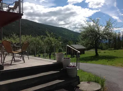 a deck with a table and chairs and a mountain at Smedsgården Hotel in Nesbyen
