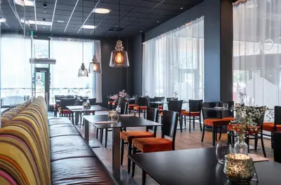a dining room with tables and chairs and windows at Thon Hotel Bjørneparken in Flå