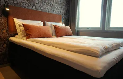 a large bed with white sheets and orange pillows at Lillehammer Turistsenter Budget Hotel in Lillehammer