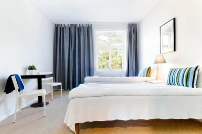 a bedroom with two beds and a desk and a window at Slottet Apartments in Tysso