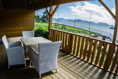 a porch with a table and chairs and a view of the beach at Lavik Fjord Hotel & Apartments in Lavik