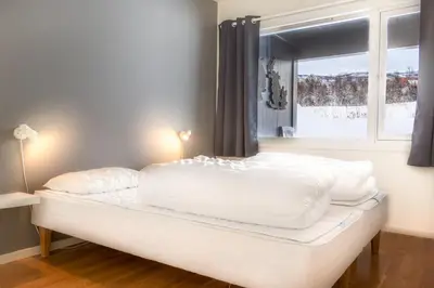 a white bed with pillows on it in a room with a window at Geilolia Ferieleiligheter in Geilo