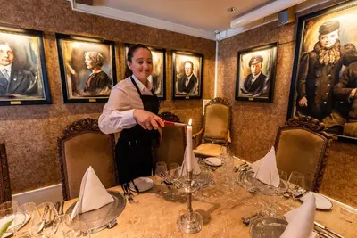 a woman is standing over a table in a restaurant at Angvik Gamle Handelssted - by Classic Norway Hotels in Angvik