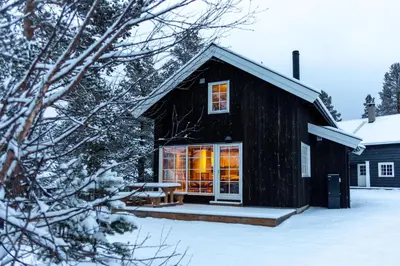 a black cabin in the snow with the door open at Geilolia Hyttetun in Geilo