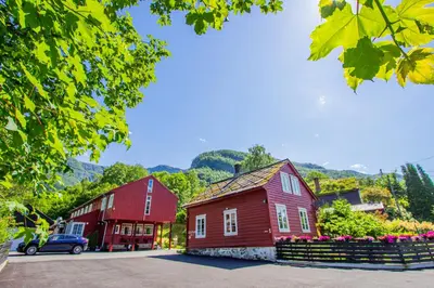 two red barns and a red house with a car at Ullensvang Gjesteheim in Lofthus
