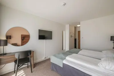 a hotel room with a bed and a desk and a mirror at Hardangerfjord Hotel in Øystese