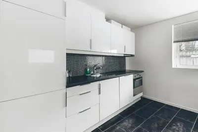 a kitchen with white cabinets and a sink at LS Apartments in Bergen