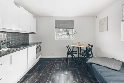 a kitchen with white cabinets and a table and chairs at LS Apartments in Bergen