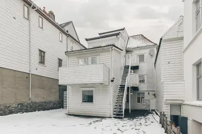 a white house with a staircase in the snow at LS Apartments in Bergen