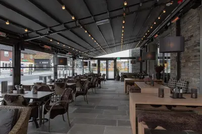 a restaurant with tables and chairs and a brick wall at Quality Hotel Skifer in Oppdal