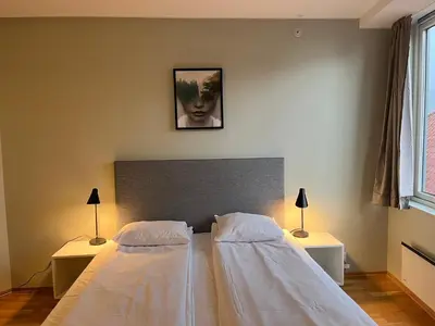 two beds in a bedroom with two lamps and a picture on the wall at City Hostel Bergen in Bergen