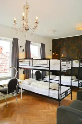 a room with three bunk beds and a chandelier at City Hostel Bergen in Bergen