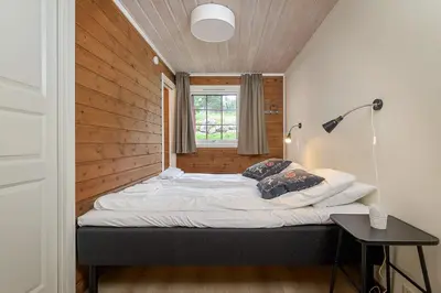 a bed in a room with a wooden wall at Lillehammer Fjellstue og Hytteutleie in Nordseter