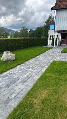 a brick walkway next to a building and a rock at Kroderen Kro & motel AS in Hamremoen
