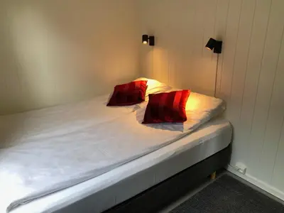 a bed with two red pillows on top of it at Tunold Gård - Gamle huset in Mindresunde