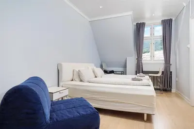 a bedroom with a bed and a blue chair at Apartment with Beautiful View to Bryggen in Bergen