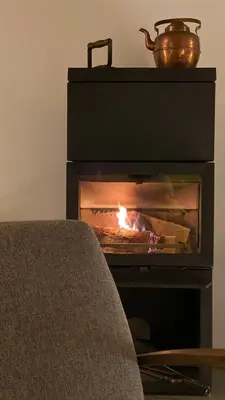a fireplace with a fire in it with a pot on top at Bjerkely, Sjusjøen in Sjusjøen