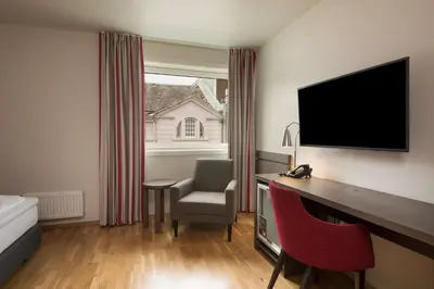a hotel room with a desk with a television and a chair at Scandic Bakklandet in Trondheim