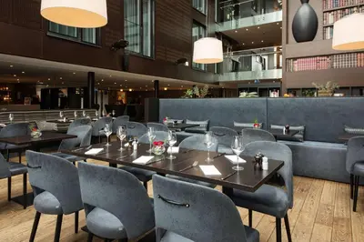 a restaurant with tables and chairs in a building at Scandic Bakklandet in Trondheim