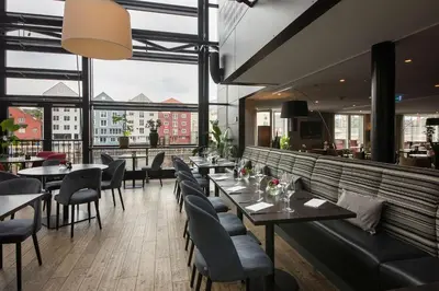 a restaurant with tables and chairs and large windows at Scandic Bakklandet in Trondheim