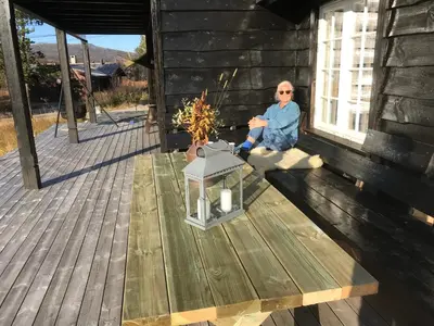 a woman sitting on the porch of a building at Remestøylflotti Hyttegrend in Hovden
