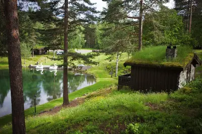 a house with a grass roof next to a river at Hunderfossen Hotel & Resort in Hafjell