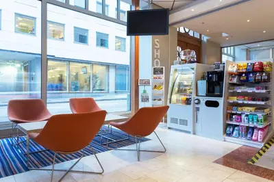 a store with orange chairs and a table and a refrigerator at Scandic Byparken in Bergen